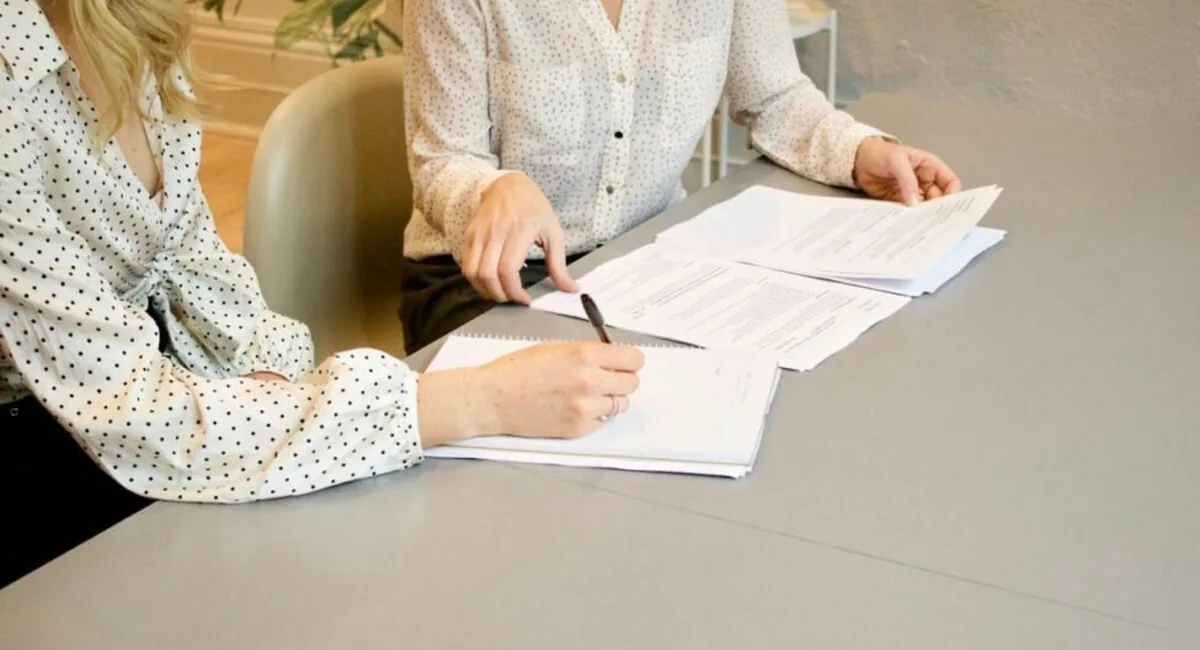 Adviser and client signing paperwork, the suitability documentation the best AI tools for financial advisors generate from the conversation