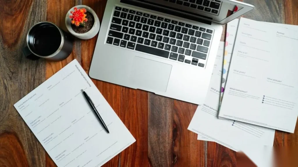 Best Answer Optimization Tools for Improving AI Visibility Desk with handwritten notes, a pen and a laptop, drafting the direct answers that answer optimization tools check