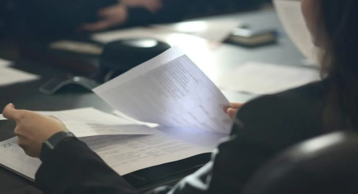 Person reading a printed policy document, the evidence review step AI compliance tools compress but do not remove