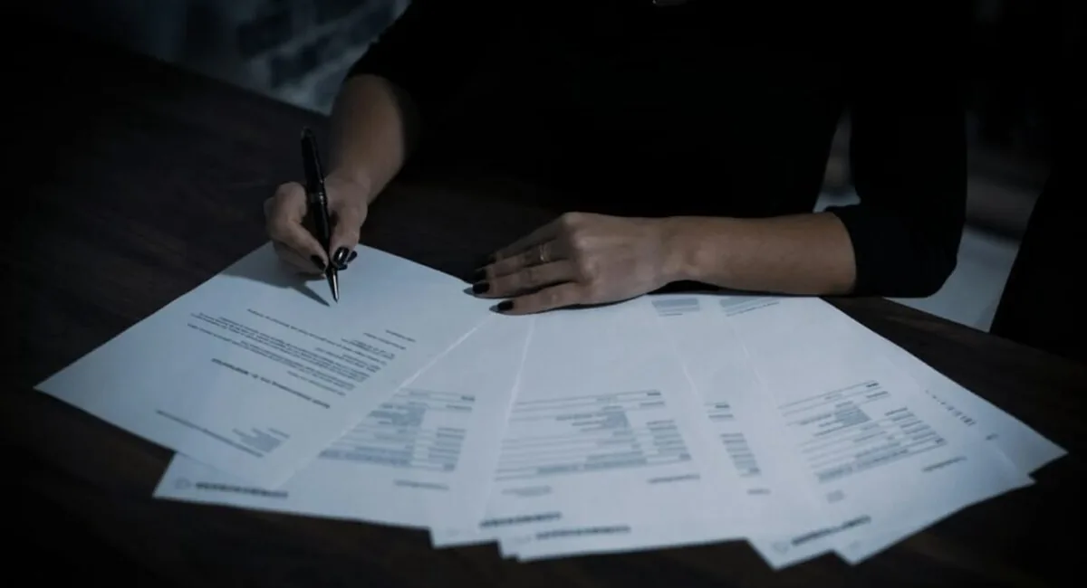 Hand signing a document, representing the named human accountability that AI governance frameworks require