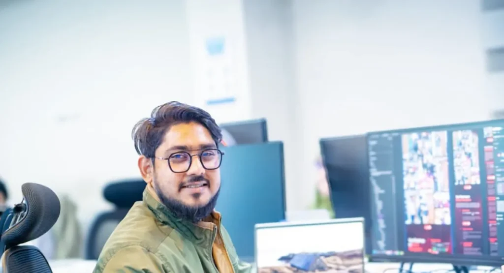 Best AI Search Monitoring Tool for SEO Professionals 2026 SEO professional smiling at a desk with monitors, the user of an AI search monitoring tool