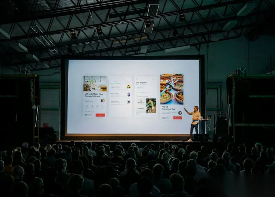 Best AI Tools for Increasing Visibility 2026: 6 Picks Presenter in front of a large screen and audience, representing the reach AI visibility tools help grow