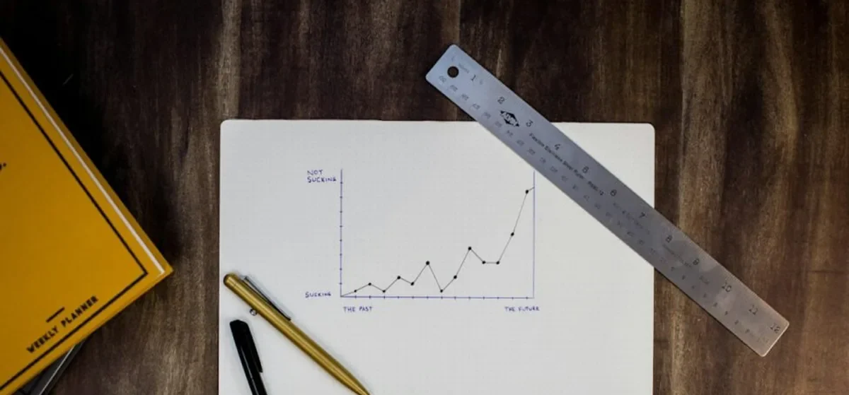 Working through AEO tool AI product Hand-drawn rising line chart on paper with a ruler and pen, tracking AEO results for an AI product