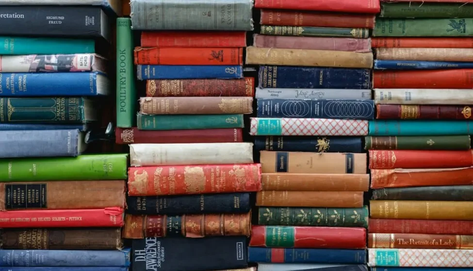 Stacked hardback books, representing the policy and regulation library AI compliance and governance tools have to track