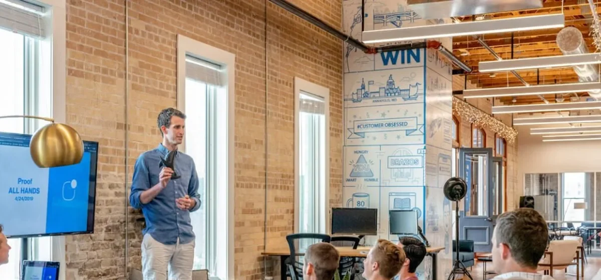 Presenter speaking to a small team in a brick-walled office, the kind of meeting AI tools for RIA firms support
