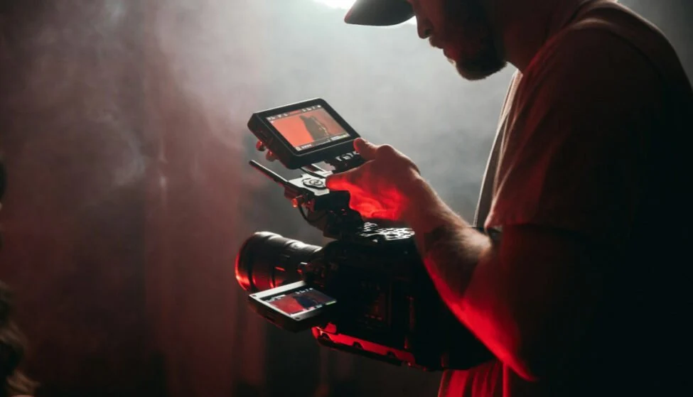 Camera operator checking footage on a monitor before narration is added with an AI voice tool