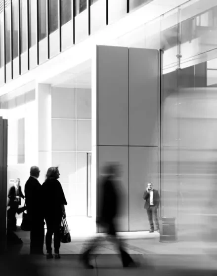 Working through competitor analysis tools AI search optimization 2025 People walking through a monochrome glass corridor, representing competitors moving through AI search results