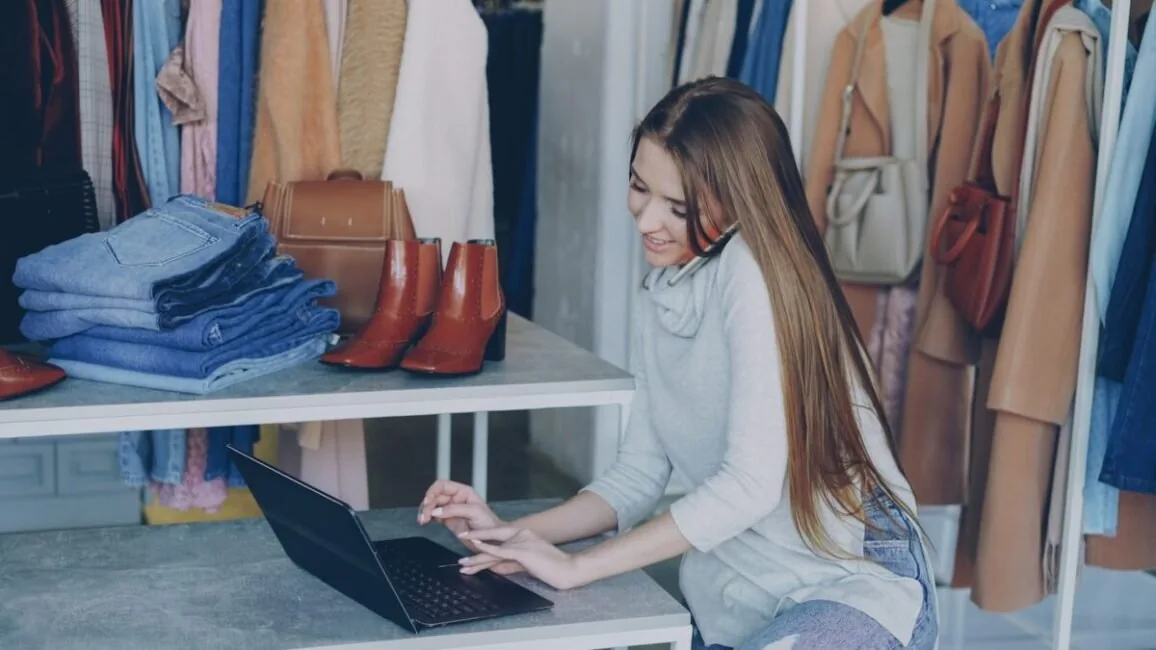 Small business owner using a laptop in her clothing shop, the setting the best AI tools for small businesses are bought for