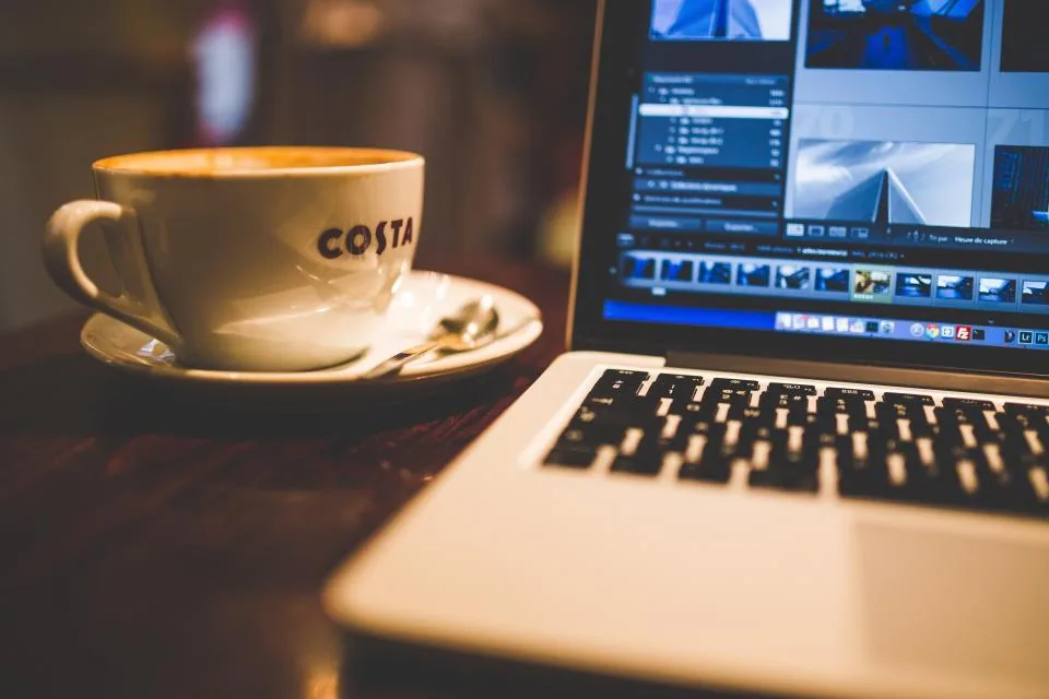 Editing on laptop with coffee Video editing on a laptop beside a cup of coffee, with AI features running on the device