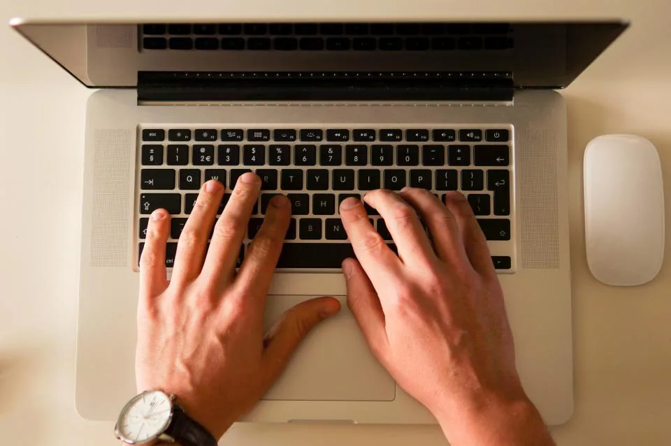 Hands typing on a laptop keyboard, automating a daily summary with a local model