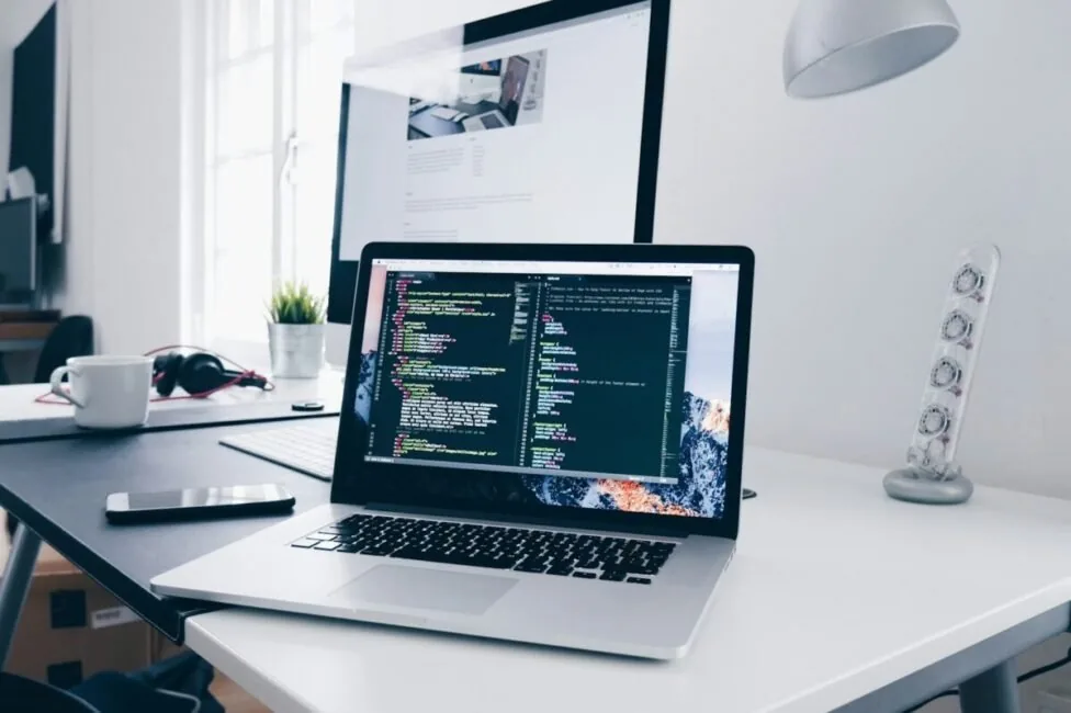 Laptop running a code editor on a white desk, illustrating the best AI evaluation tools for production