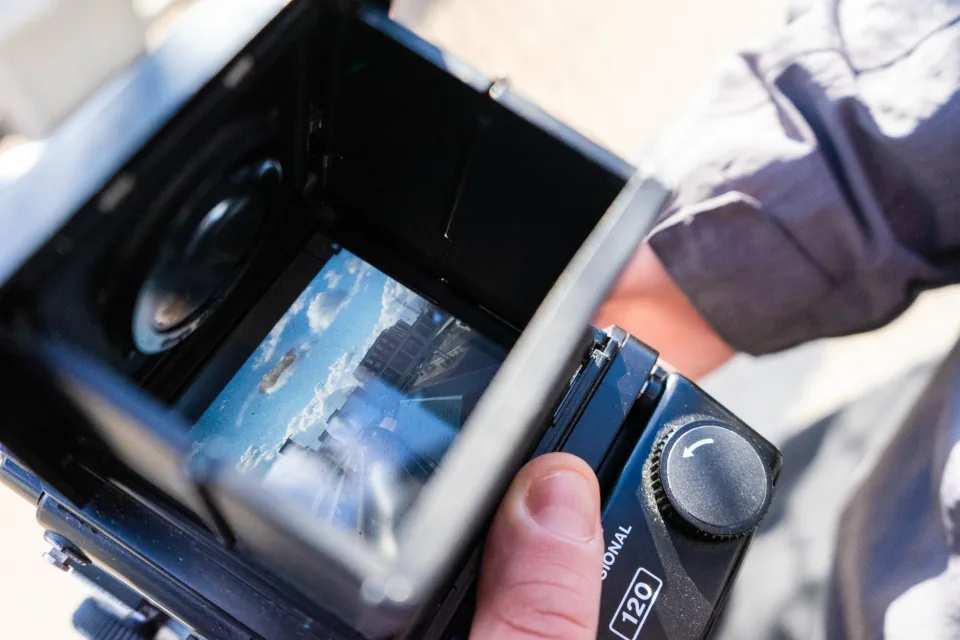 Twin-lens camera held in hand, framing a shot that could be animated by a local video model